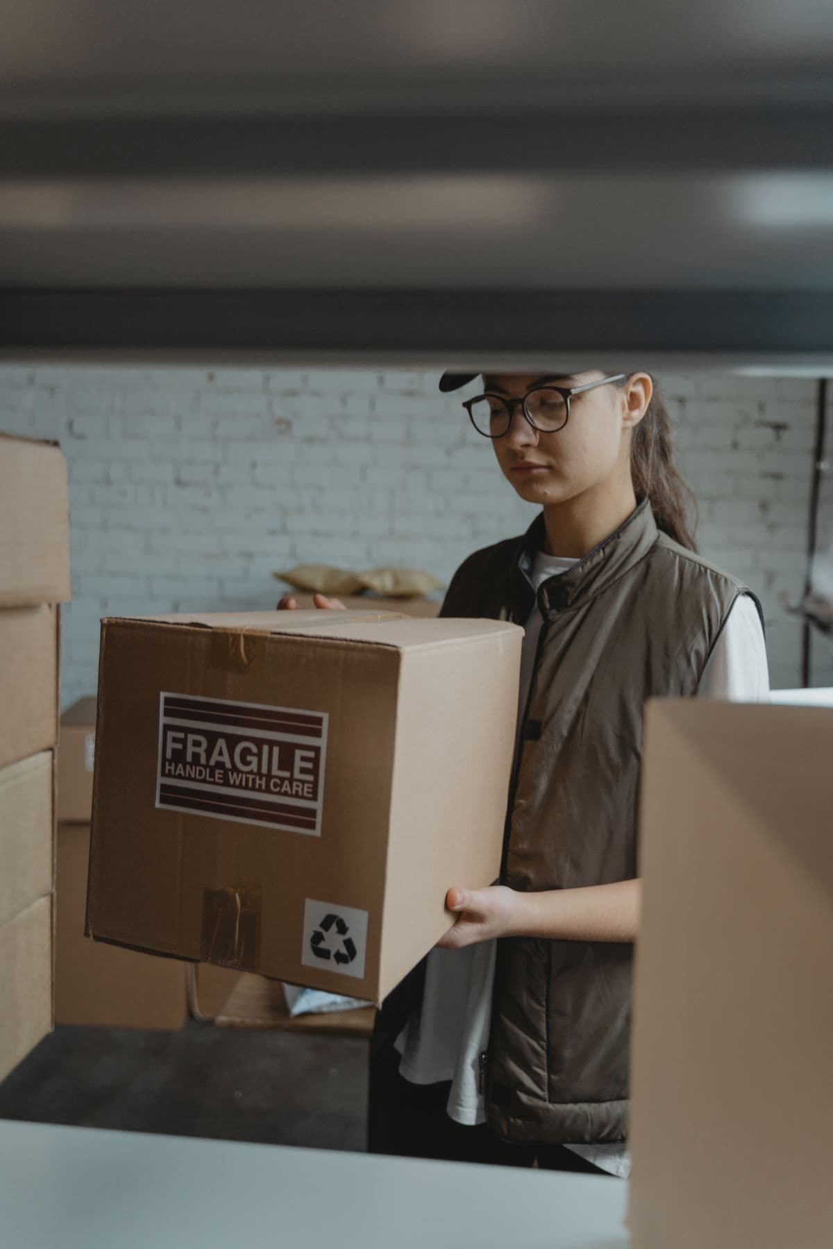 A uniformed worker carrying a labeled box out for recycling